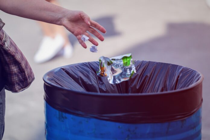 Man,Throws,Garbage,Into,A,Garbage,Can,On,The,Street