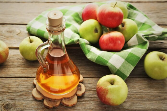 Apple,Vinegar,In,Glass,Bottle,On,Grey,Wooden,Table